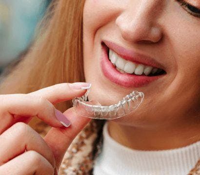Smiling woman holding her ClearCorrect aligners.