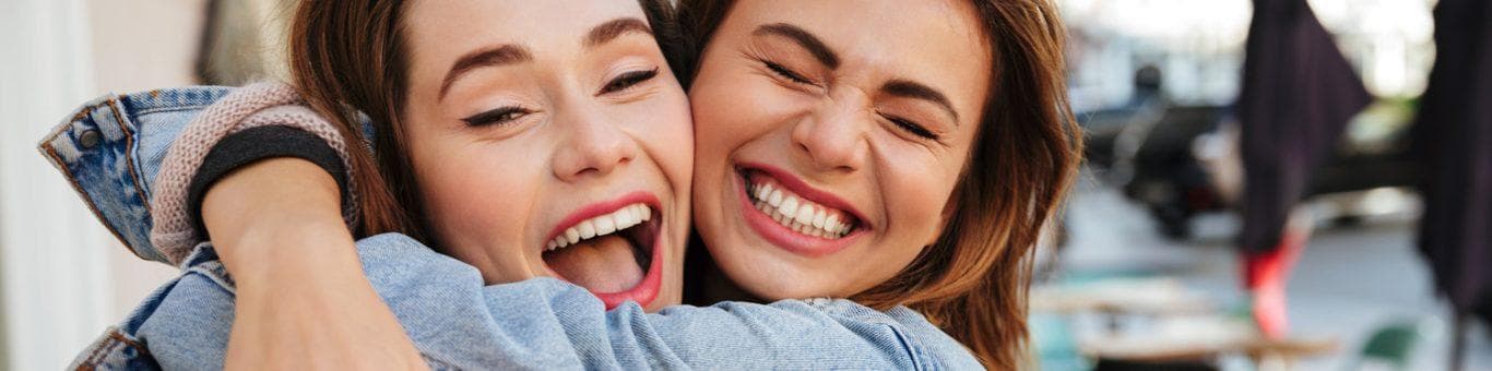 Two brunette women hugging and smiling.