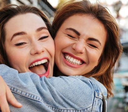 Two brunette women hugging and smiling.