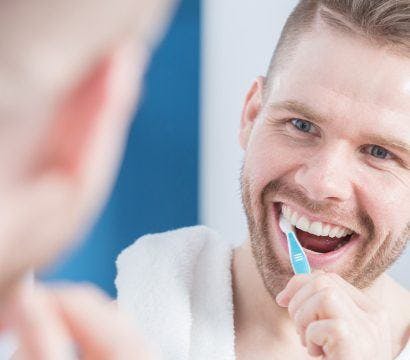 Man brushing teeth in front of mirror.