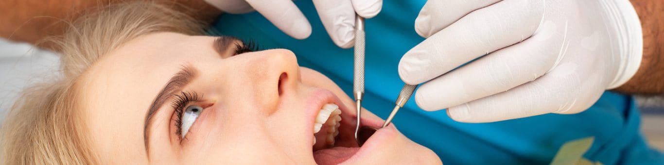 Caucasian blonde woman getting her teeth checked.