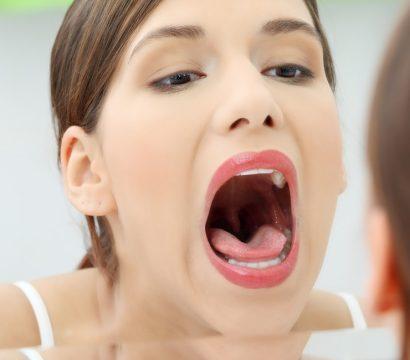 Caucasian woman in ponytail with open mouth looking at mirror.