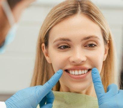 A young woman checking her teeth in the mirror while her dentist explains a procedure.