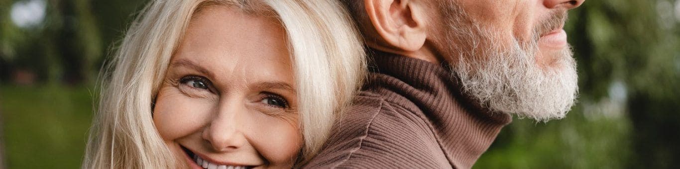 Blonde woman smiling while hugging man in brown turtleneck.