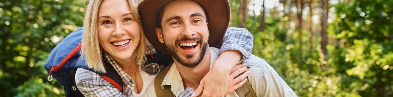 Young laughing couple hiking in the woods posing for a photo.