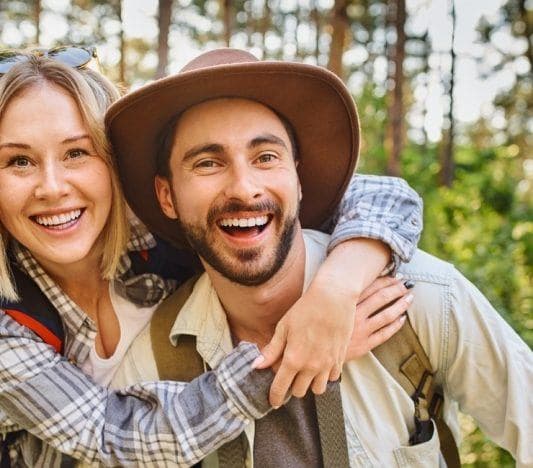 Young laughing couple hiking in the woods posing for a photo.