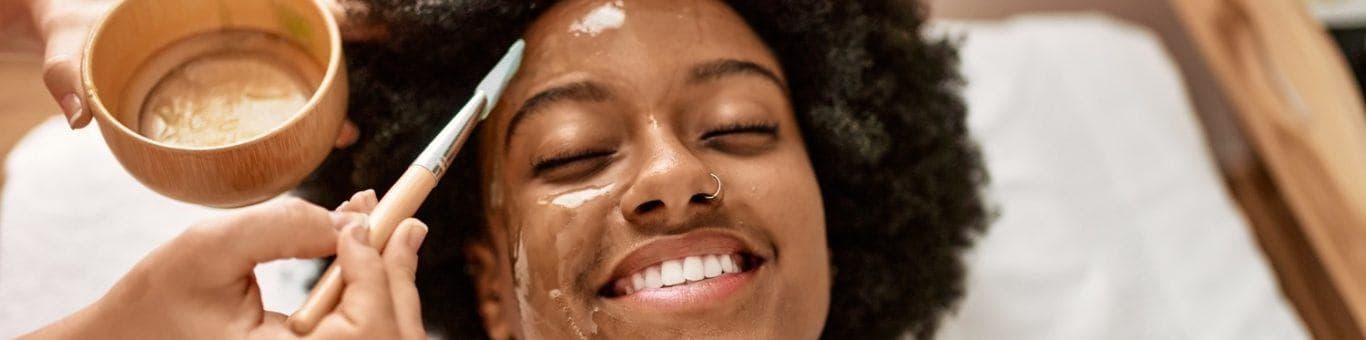 African woman having facial in spa.