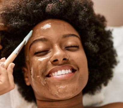 African woman having facial in spa.