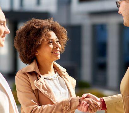 Three people shaking hands outdoors.