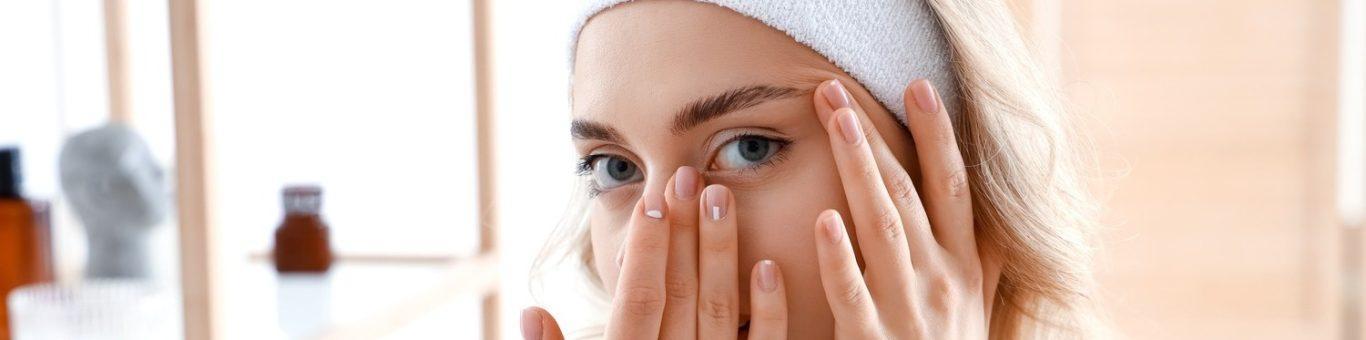 Blonde woman massaging her eye area.