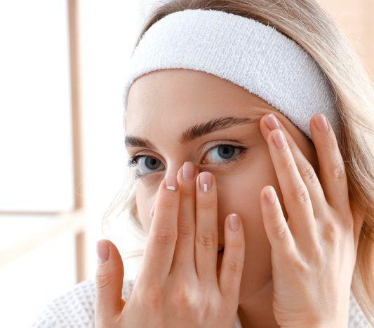 Blonde woman massaging her eye area.