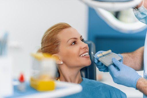 A woman getting her teeth colour reviewed by a dentist.