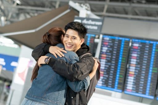 A man smiling while hugging his partner.