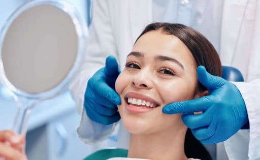 Woman smiling at the dentist holding a hand mirror.