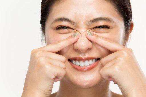 Asian woman pointing at the wrinkles on her nose.