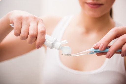 Close-up of woman’s hand putting toothpaste on her toothbrush.