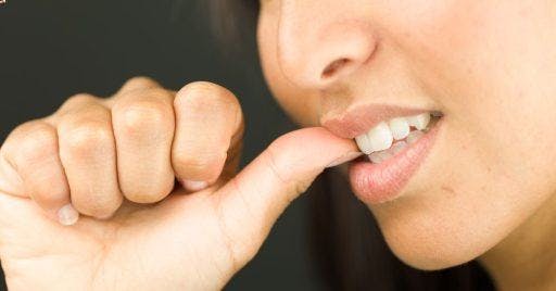 Cropped photo of woman biting her thumb.