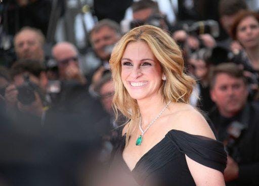 Julia Roberts in black smiling against a blurred crowd.