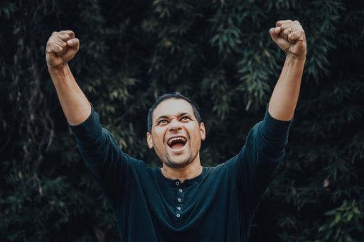 Man happily cheering with fists in the air in a victory pose.