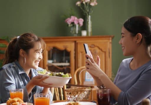 Two female friends happily taking photos of food.